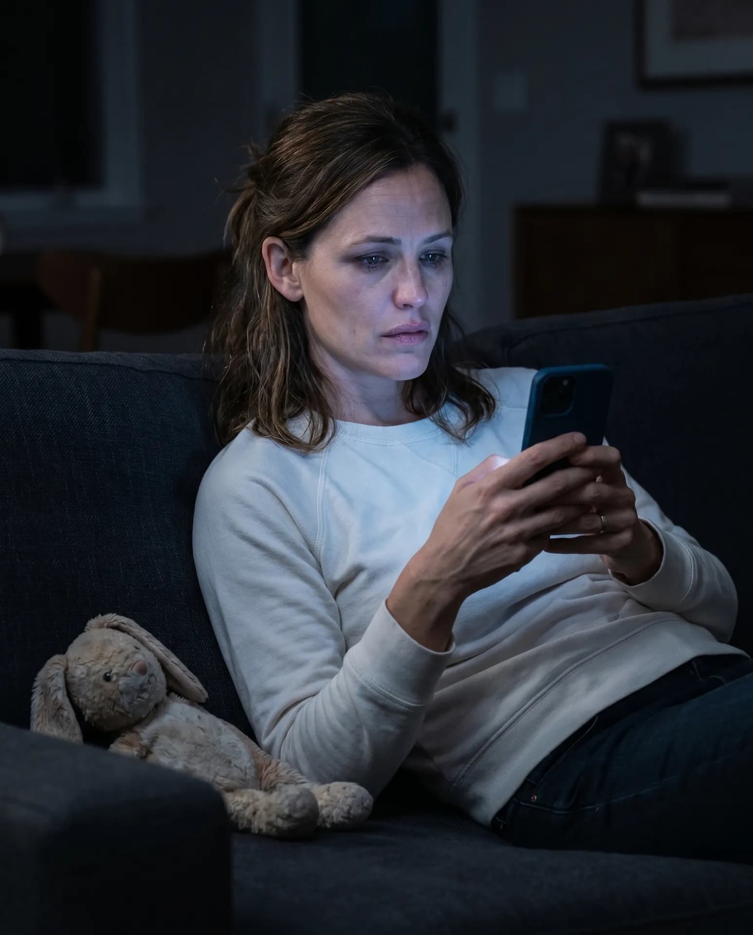 A tired mom on the couch at night, lit only by her phone